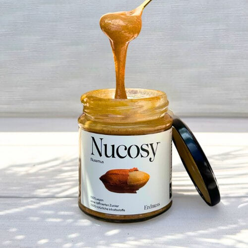 Cremiges Nucosy Erdnussmus, langsam vom Löffel fließend – 100 % Nüsse, ohne Zuckerzusatz.